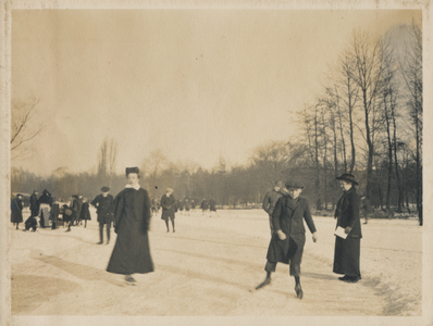 879317 Afbeelding van schaatsende en wandelende mensen op een ijsbaan, vermoedelijk in het Wilhelminapark te Utrecht.